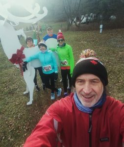 Runners posing beside a white reindeer.