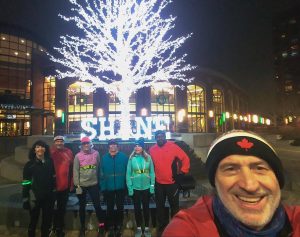 Runners standing in front of a brightly lite tree with the words shine.
