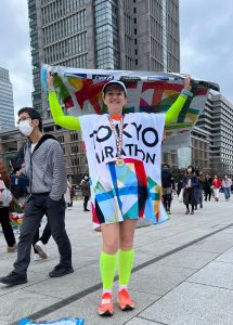 Ines holding up a flag for the Tokyo race. She is wearing her medal.