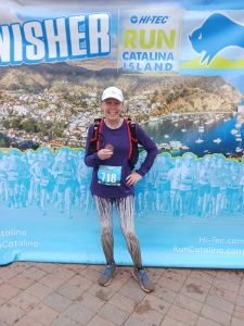 Christine smiling with her medal. Her tights and shoes are covered in mud.